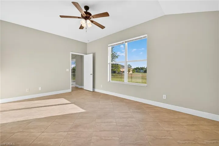Empty room with a ceiling fan and lofted ceiling
