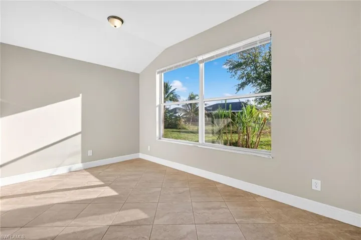 Empty room featuring lofted ceiling and light tile patterned flooring