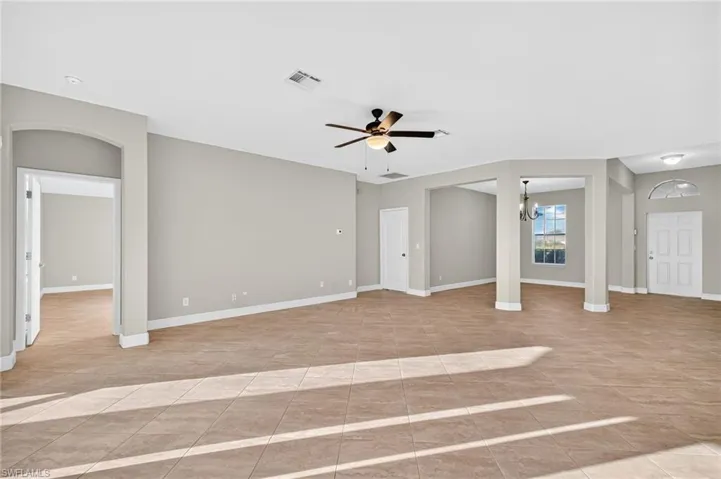 Unfurnished living room featuring ceiling fan, a chandelier, and light tile patterned floors