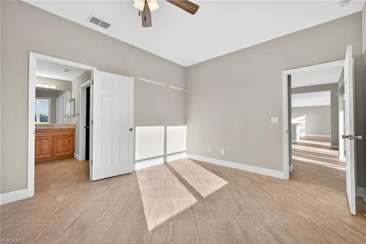Unfurnished bedroom featuring light tile patterned flooring, ceiling fan, and connected bathroom