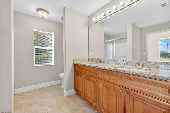 Bathroom featuring double vanity, light tile patterned floors, and a stall shower