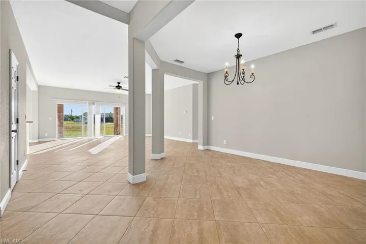 Unfurnished room featuring a chandelier, light tile patterned floors, and ceiling fan