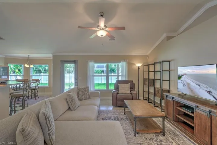 Living room with ceiling fan, crown molding, and lofted ceiling