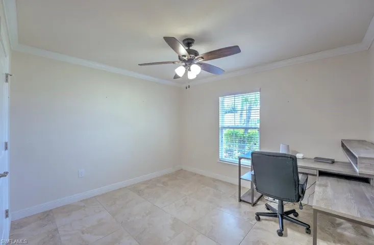 Unfurnished office featuring ceiling fan, crown molding, and light tile patterned floors