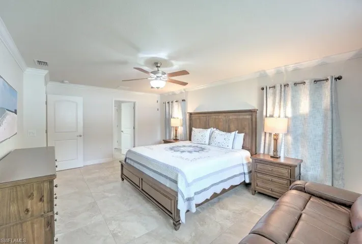 Tiled bedroom with ornamental molding and ceiling fan