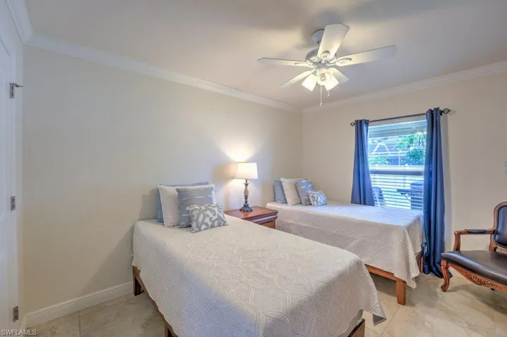 Tiled bedroom featuring ornamental molding and ceiling fan