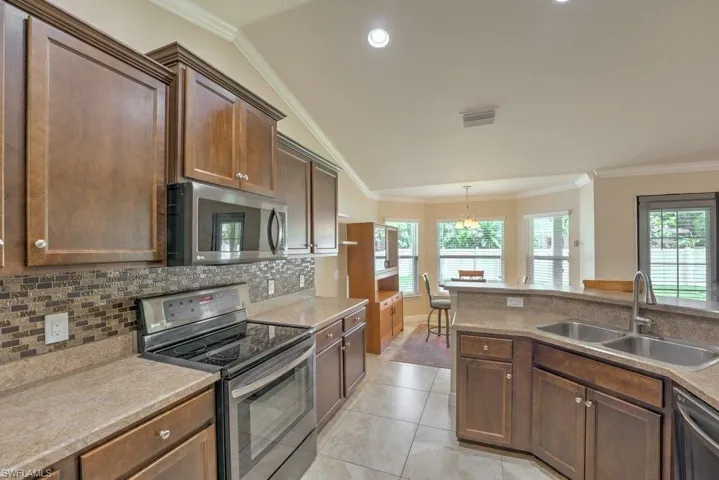 Kitchen with appliances with stainless steel finishes, light tile patterned flooring, crown molding, and sink