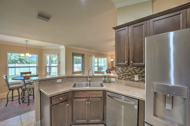 Kitchen featuring plenty of natural light, appliances with stainless steel finishes, kitchen peninsula, dark brown cabinets, and sink
