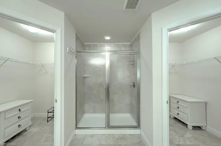Bathroom featuring walk in shower, vanity, and tile patterned flooring