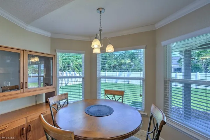 Dining room featuring a textured ceiling, crown molding, and an inviting chandelier