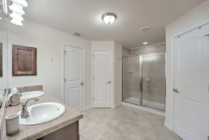 Bathroom featuring walk in shower, double vanity, and tile patterned flooring