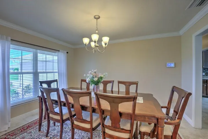 Tiled dining room featuring a notable chandelier and crown molding