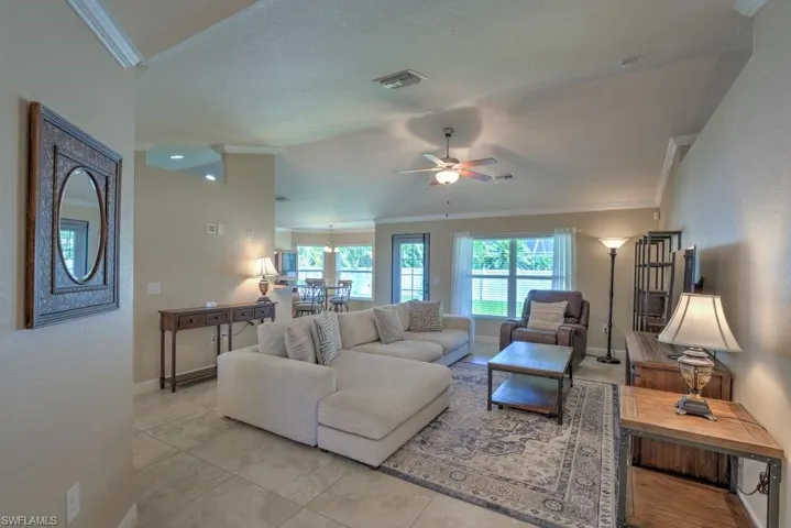 Living room featuring ceiling fan, light tile patterned flooring, and ornamental molding