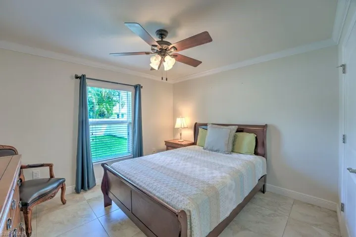 Bedroom with ceiling fan, light tile patterned flooring, and ornamental molding