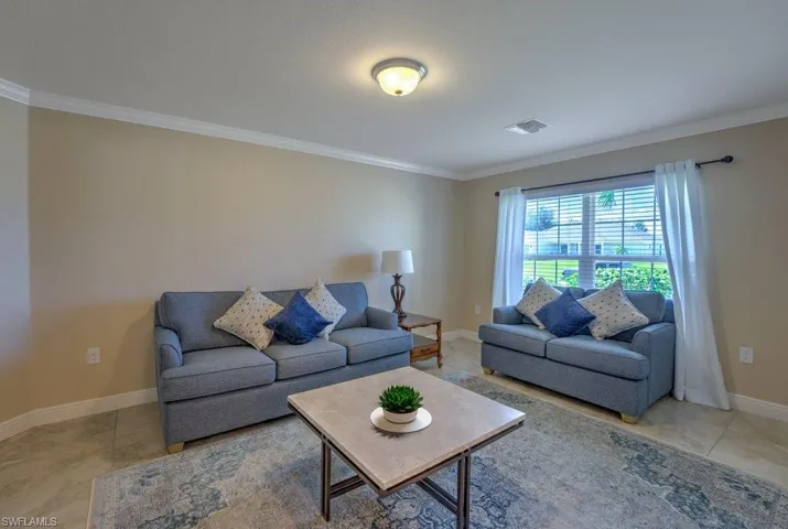 Living room with crown molding and light tile patterned floors