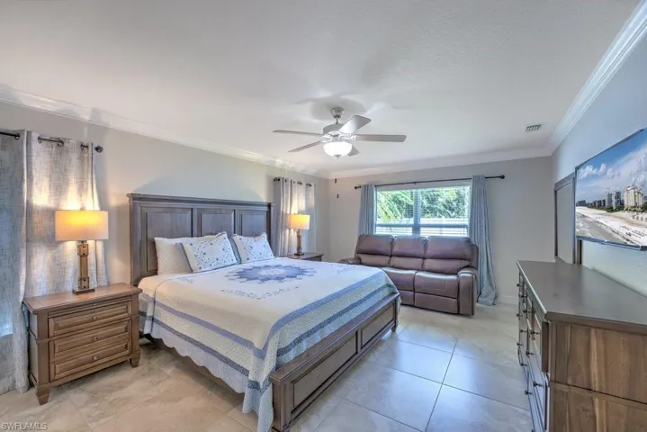 Tiled bedroom featuring ceiling fan and ornamental molding