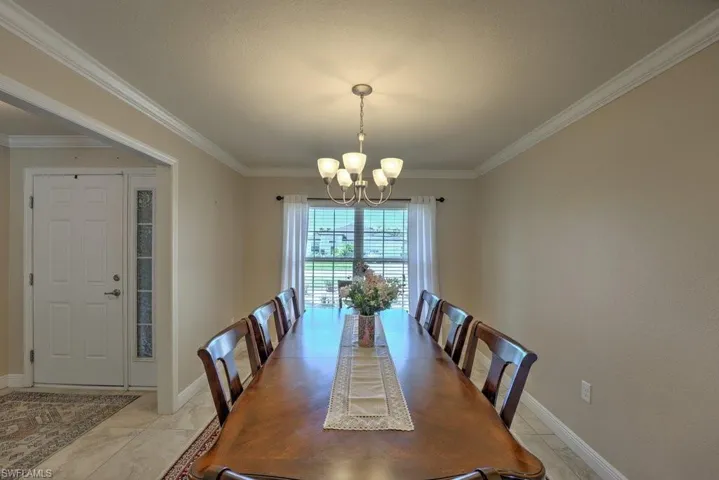 Dining space featuring a chandelier, ornamental molding, and tile patterned flooring