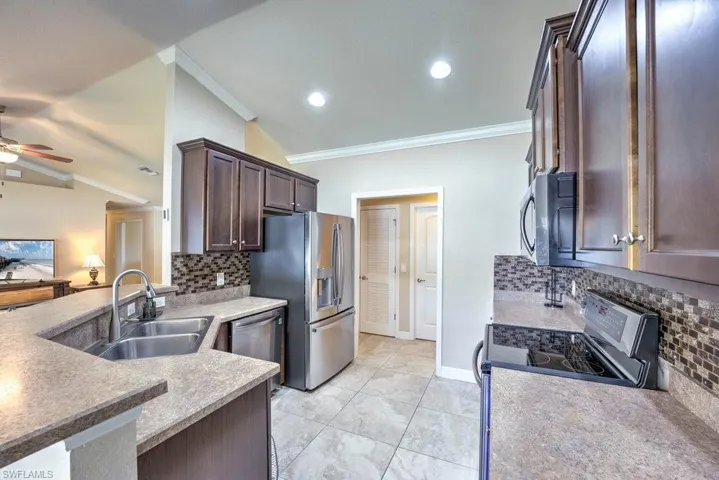 Kitchen with stainless steel appliances, backsplash, ornamental molding, ceiling fan, and sink