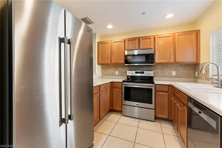Kitchen with appliances with stainless steel finishes, light countertops, tasteful backsplash, brown cabinets, and recessed lighting