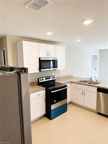 Kitchen featuring white cabinetry, light-toned stone-finish countertops, stainless steel appliances, and recessed lighting