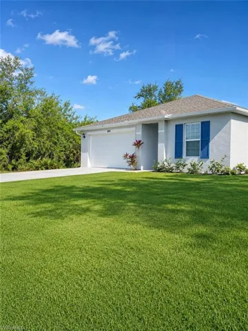 Stucco exterior with a shingle roof, attached garage, concrete driveway, and front landscaping