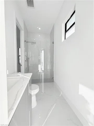 Full bathroom with marble tiled floors, toilet, a marble finish shower, vanity, and recessed lighting