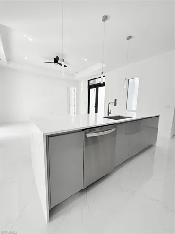 Kitchen featuring dishwashing machine, modern cabinets, a sink, gray cabinets, and a raised ceiling