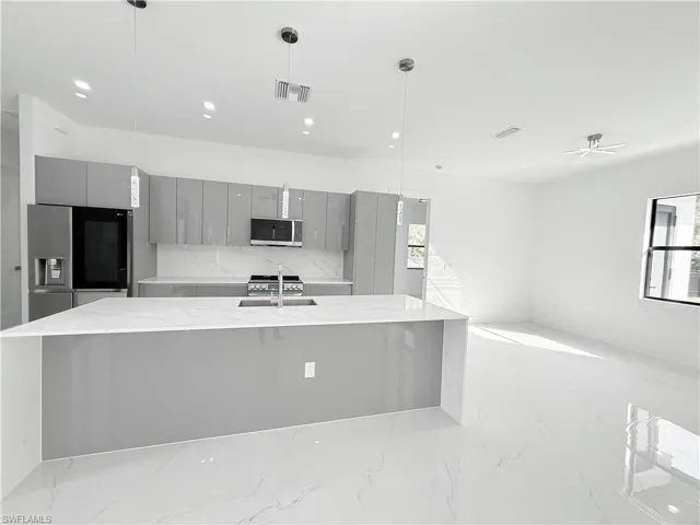Kitchen with gray cabinetry, stainless steel appliances, modern cabinets, a large island, and a sink