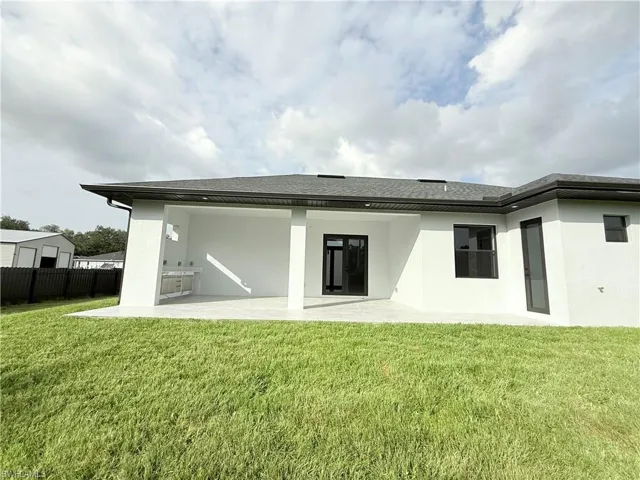 Back of property with a patio area, stucco siding, and a shingled roof