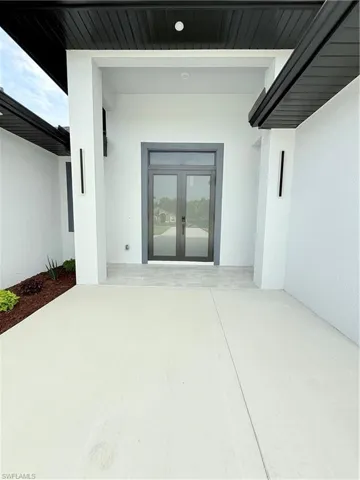 View of exterior entry featuring french doors, stucco siding, and a patio