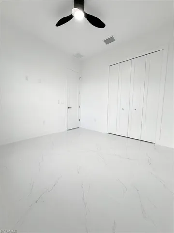 Unfurnished bedroom with light marble finish flooring, baseboards, a closet, and ceiling fan