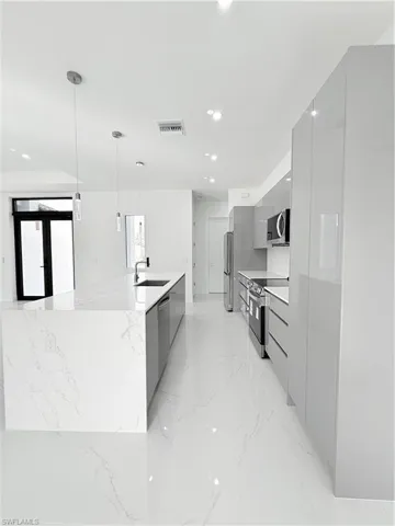 Kitchen with modern cabinets, range, a sink, gray cabinets, and light marble finish floors