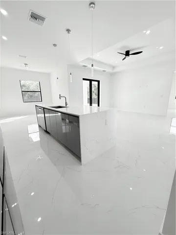 Kitchen with modern cabinets, open floor plan, light marble finish flooring, a sink, and plenty of natural light