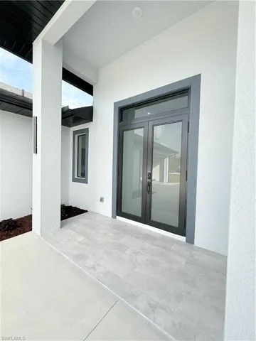 Entrance to property with stucco siding, french doors, and a patio