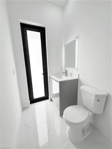 Bathroom with marble finish flooring, toilet, vanity, and baseboards