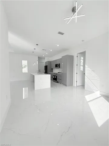 Unfurnished living room with light marble finish floors, baseboards, and recessed lighting