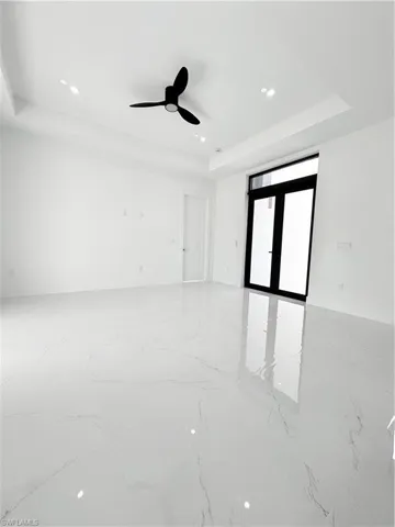 Spare room featuring a tray ceiling, recessed lighting, ceiling fan, baseboards, and light marble finish floors