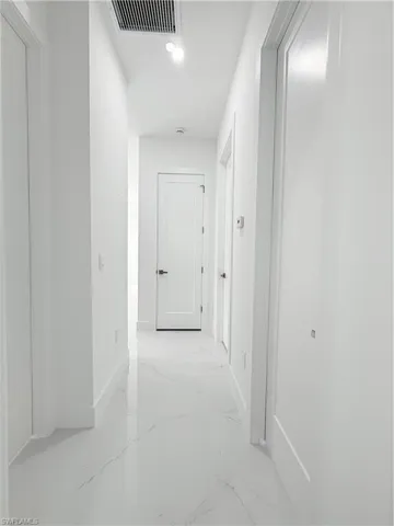 Hallway featuring light marble finish flooring and baseboards
