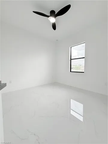 Unfurnished room with marble finish floors, baseboards, and ceiling fan