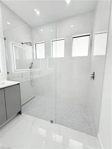 Bathroom with vanity, a marble finish shower, marble tiled flooring, and recessed lighting