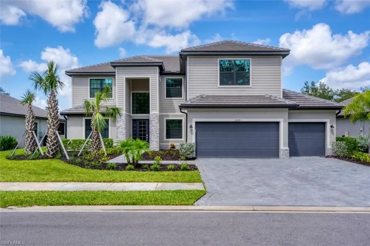 View of front of home featuring a tiled roof, stone siding, decorative driveway, stucco siding, and a garage