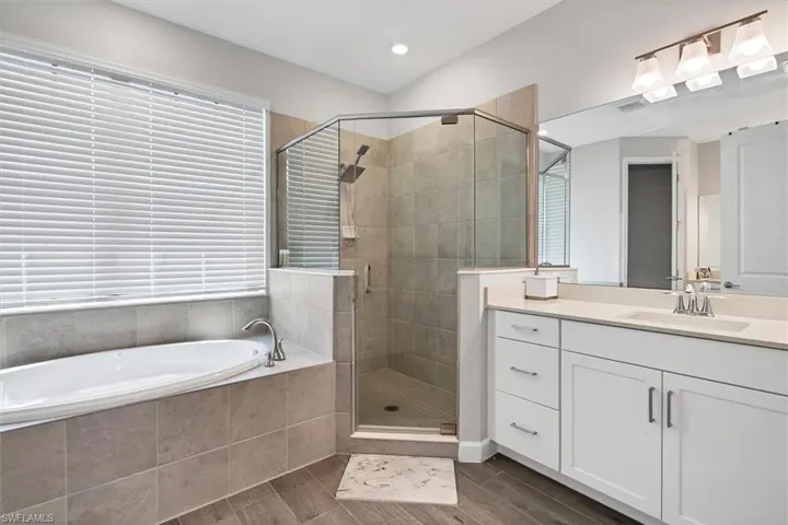 Full bath with vanity, a bath, a shower stall, wood finish floors, and recessed lighting