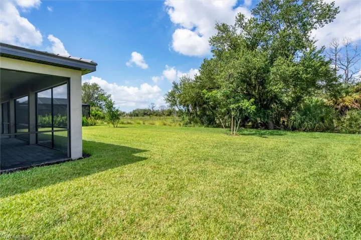 View of grassy yard featuring a sunroom