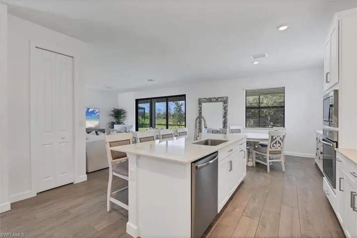 Kitchen with white cabinets, a breakfast bar area, stainless steel appliances, light wood finished floors, and recessed lighting