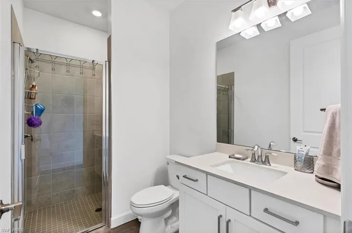 Bathroom featuring vanity, a stall shower, recessed lighting, and dark wood-style floors