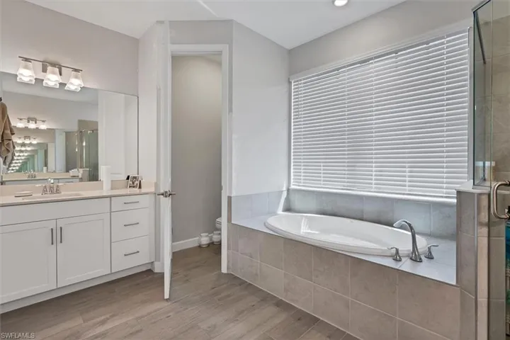 Full bath featuring a stall shower, vanity, a bath, and light wood finished floors