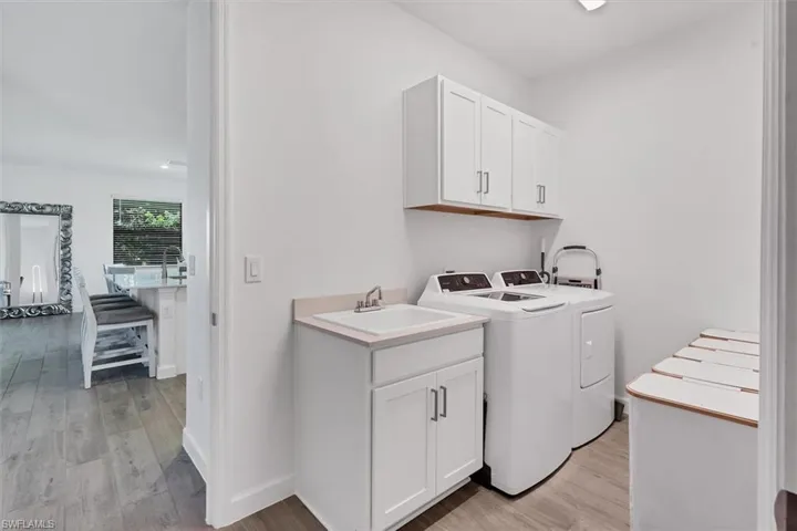 Washroom with light wood-style flooring, washing machine and dryer, and cabinet space