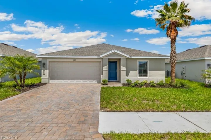 Single-story residence featuring a two-car garage, paver driveway, and a prominent blue entry door