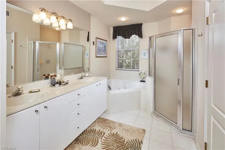 En suite bathroom with a soaking tub, separate tile shower, and dual sinks.