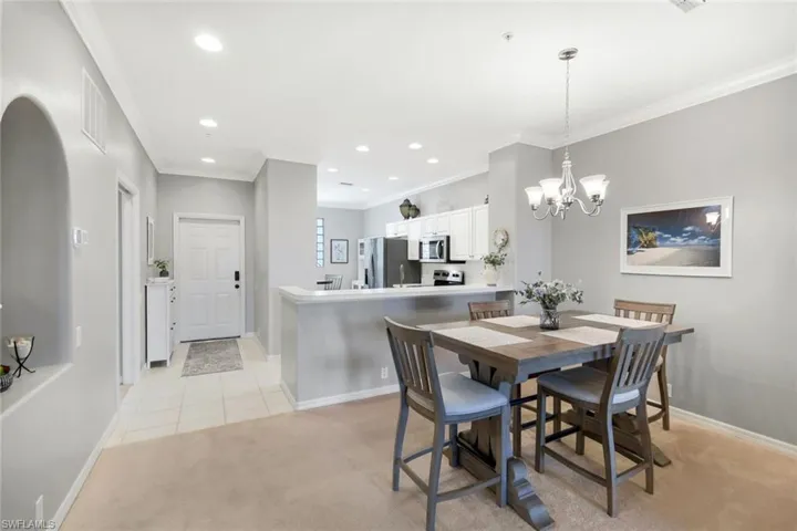 Dining area featuring a notable chandelier, light tile patterned floors, and ornamental molding